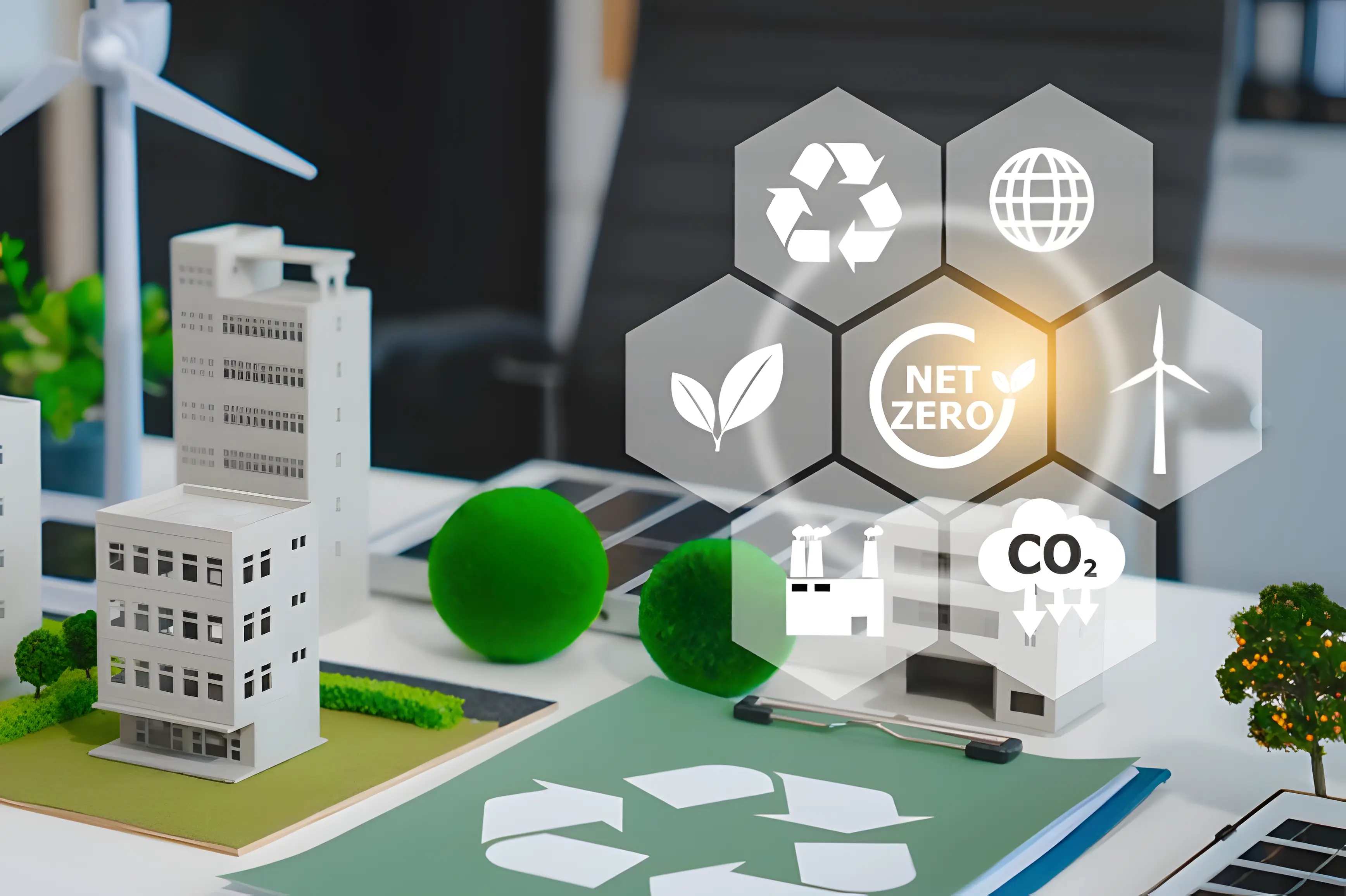 Model of an eco-friendly city with buildings, a wind turbine and solar panels, overlaid with icons for recycling, renewable energy, CO₂ emissions and a net zero goal.